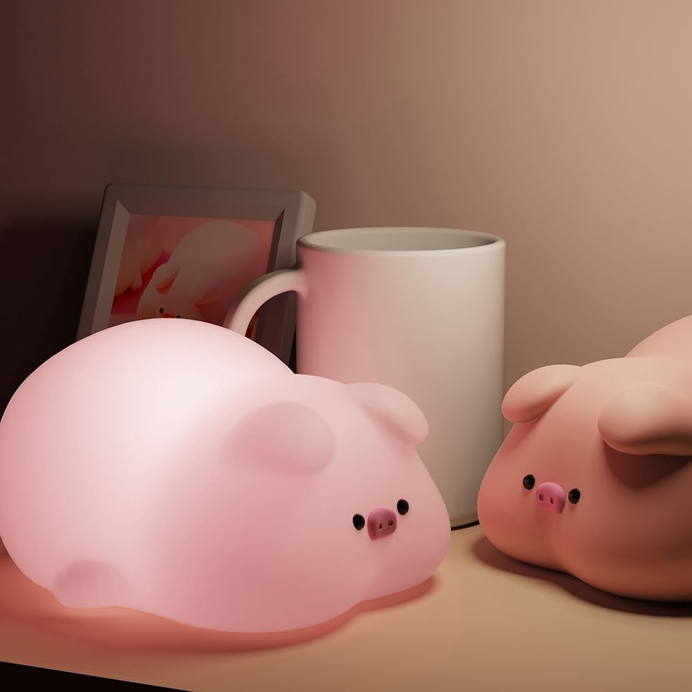 Two pig-shaped toy lights sitting next to each other on a bedside table in a child's room.